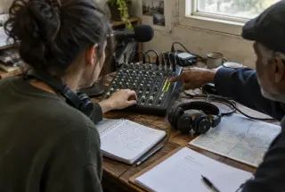 Volunteer learning audio mixing from a mentor during a community radio workshop